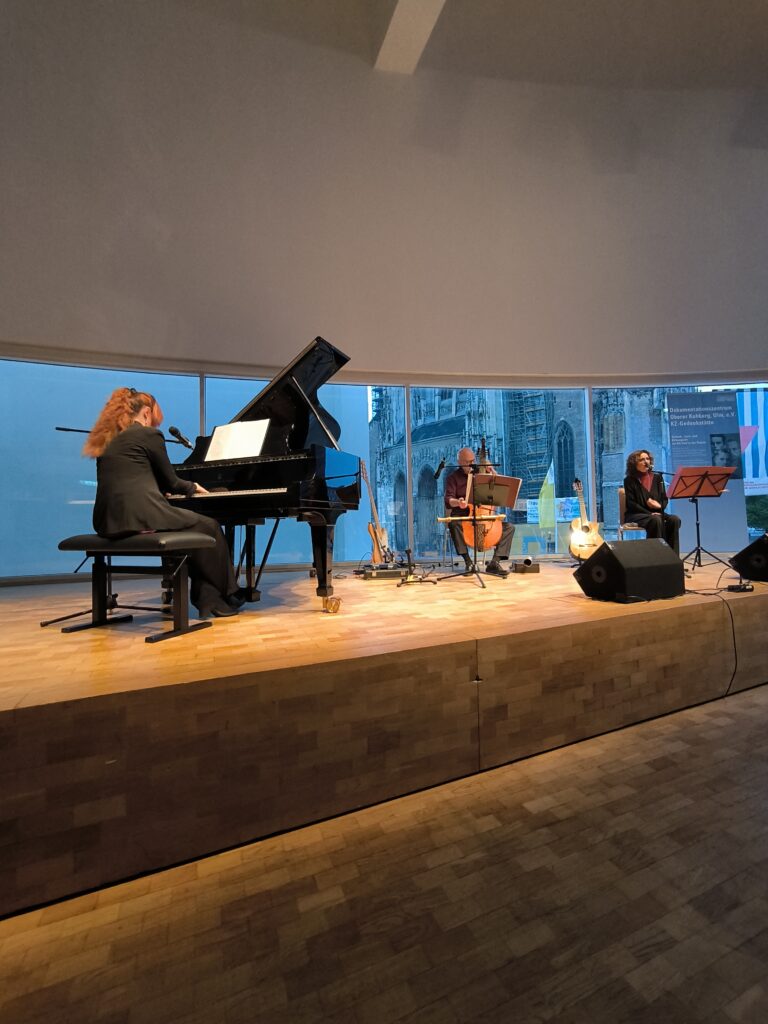 Auf dem Bild ist Turiner Trio „La Desbandá“ bei seinem Auftritt zum 80. Jahrestag der Befreiung vom Faschismus im Stadthaus Ulm zu sehen. Das Trio besteht, wie auf dem Bild zu sehen aus Tiziana Cappellino am Flügel, López Massimo Sartori am Kontrabass und der Gitarristin und Sängerin Angeles Agyado. Es sang Lieder des Widerstands gegen das Franco-Regimes, die Nazidiktatur sowie antifaschistische und Antikriegslieder. Foto: Johannes Glembek
