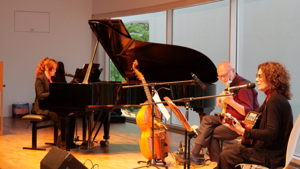 Auf dem Bild ist Turiner Trio „La Desbandá“ bei seinem Auftritt zum 80. Jahrestag der Befreiung vom Faschismus im Stadthaus Ulm zu sehen. Das Trio besteht, wie auf dem Bild zu sehen aus Tiziana Cappellino am Flügel, López Massimo Sartori mit einer E-Guitarre und der Gitarristin und Sängerin Angeles Agyado. Es sang Lieder des Widerstands gegen das Franco-Regimes, die Nazidiktatur sowie antifaschistische und Antikriegslieder. Foto: Konrad Sedding